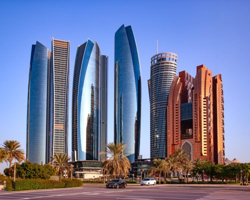 UAE, ABU DHABI, NOVEMBER, 18, 2021 - Skyscrapers surrounded by a green park of palm trees and fountains at sunset in Abu Dhabi, capital of the United Arab Emirates.